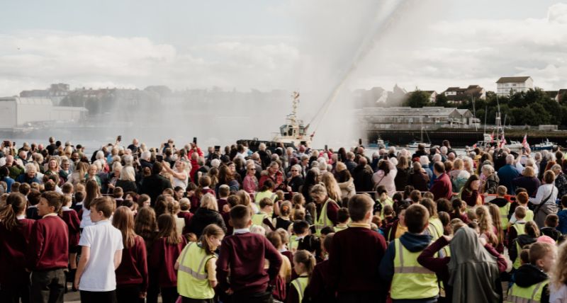 Crowds watch the Svitzer tug water jets at the unveiling of the Herring Girl on sculpture on the Fish Quay in September 2023 Crowds watch the Svitzer tug water jets at the unveiling of the Herring Girl sculpture in 2023