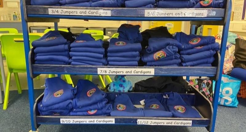 Rack with various sized school jumpers on it