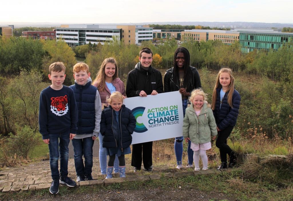 Young people in SIlverlink Biodivesity Park holding the council's new Action on Climate Change logo