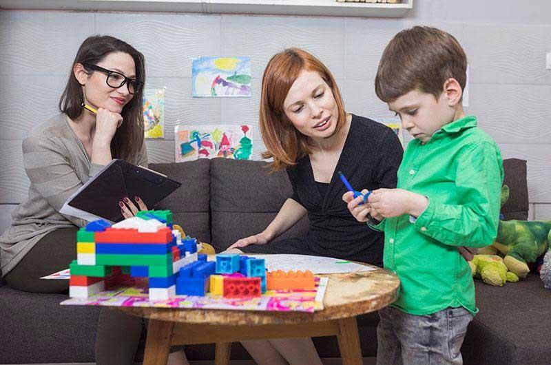 A child playing, being evaluated by two professionals