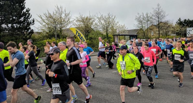 Group of people in various colours of clothing running on a road