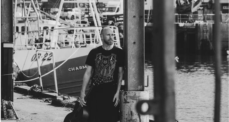 A black and white photo of Olly Armstrong on North Shields Fish Quay with fishing boats behind