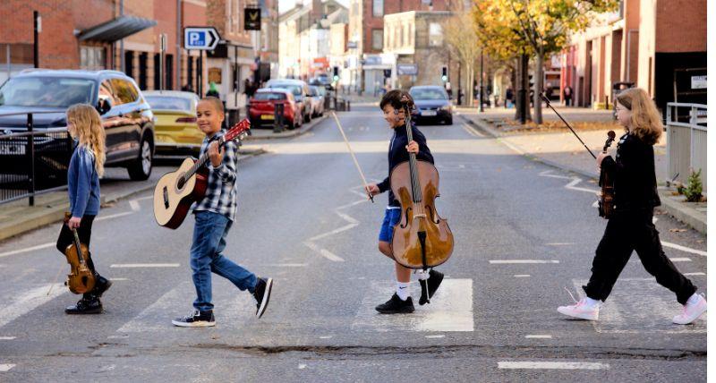 Children carrying musical instruments walk across the zebra crossing on Saville Street in North Shields 