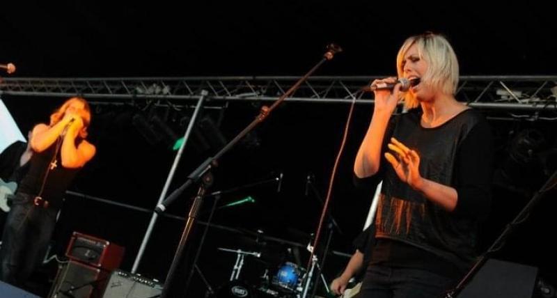 Bernii Mac performing live on stage with other musicians in the background